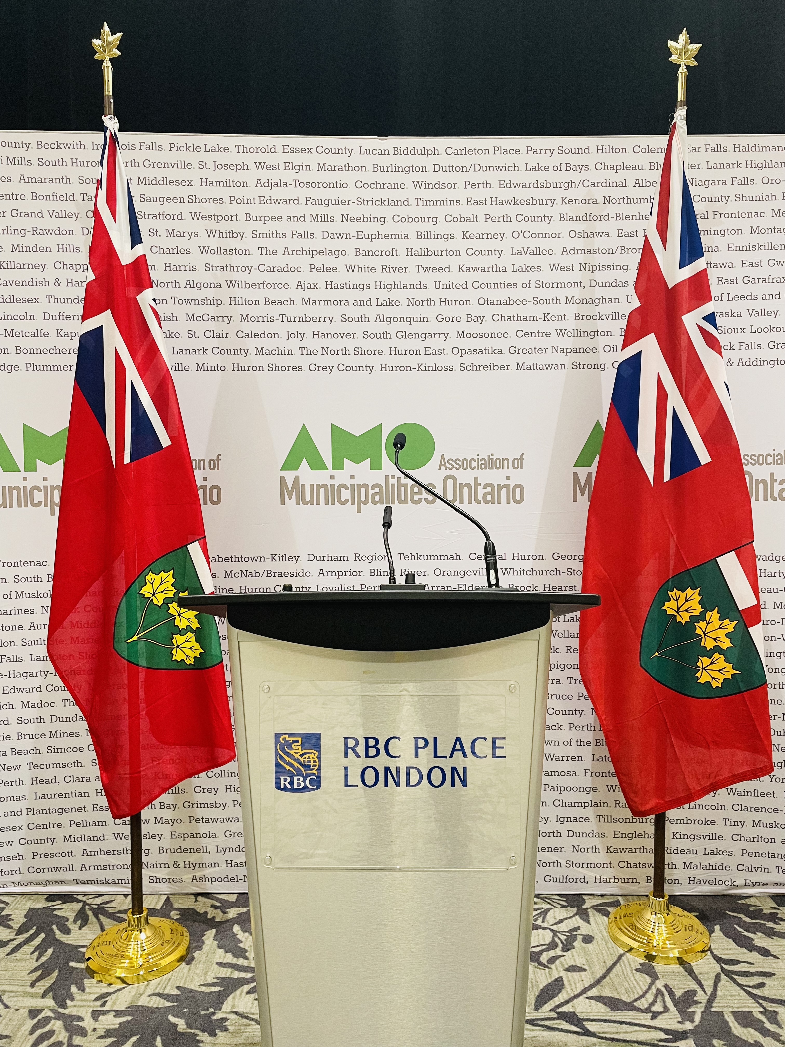 An image of a podium with a microphone and banner that reads "Association of Municipalities of Ontario".