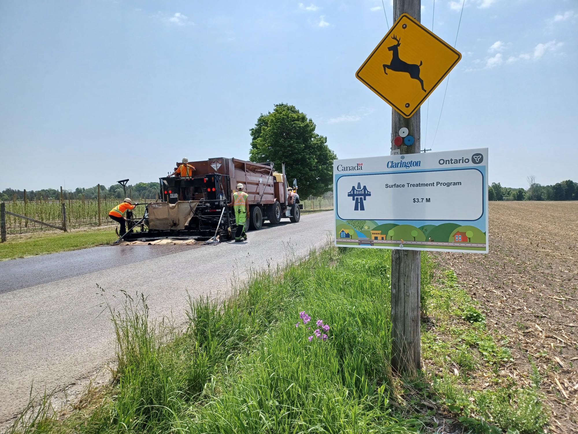 Workers putting sealant on a rural roadway in Clarington. 