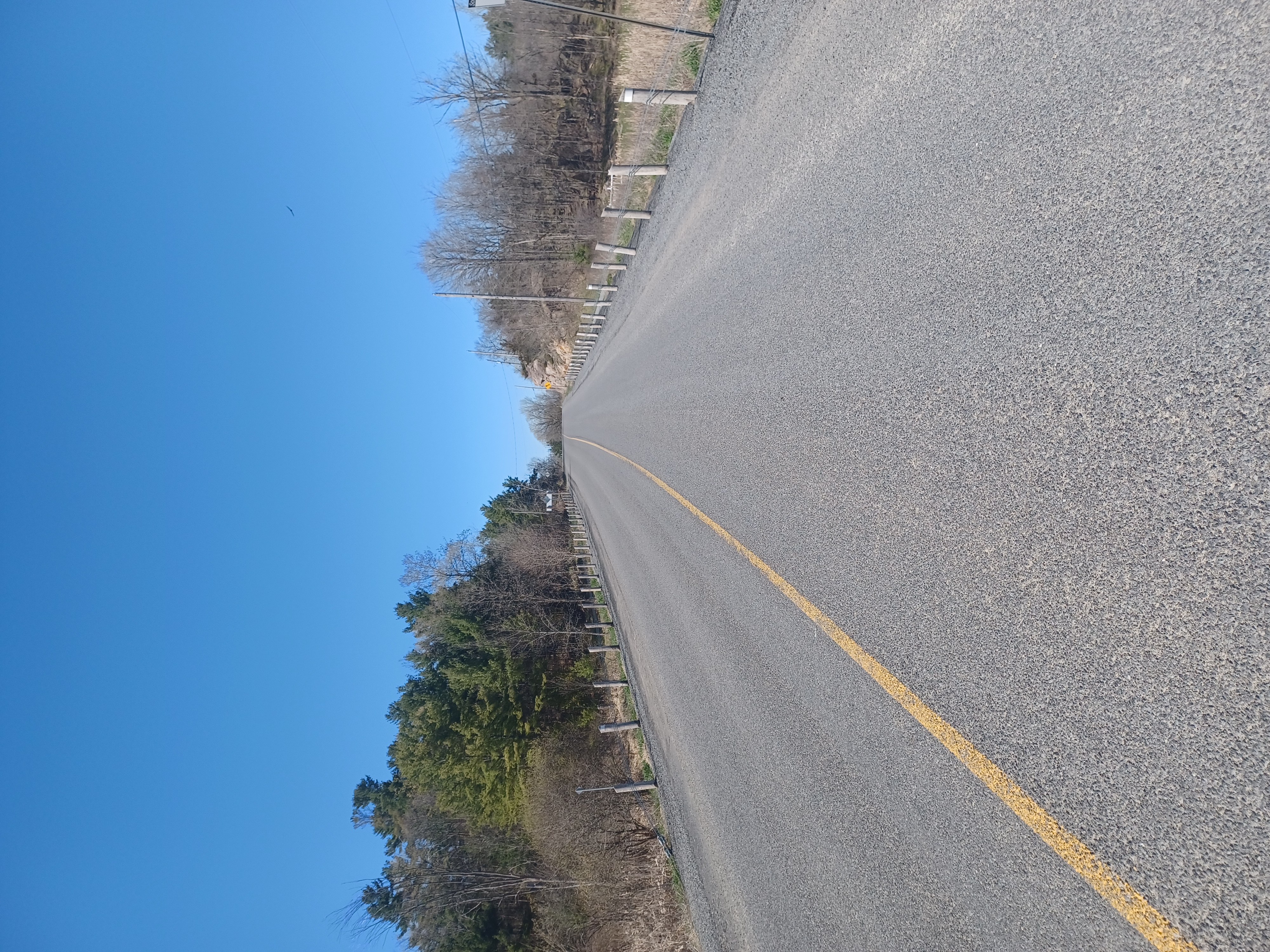 A freshly paved rural roadway under a sunny, blue sky. 