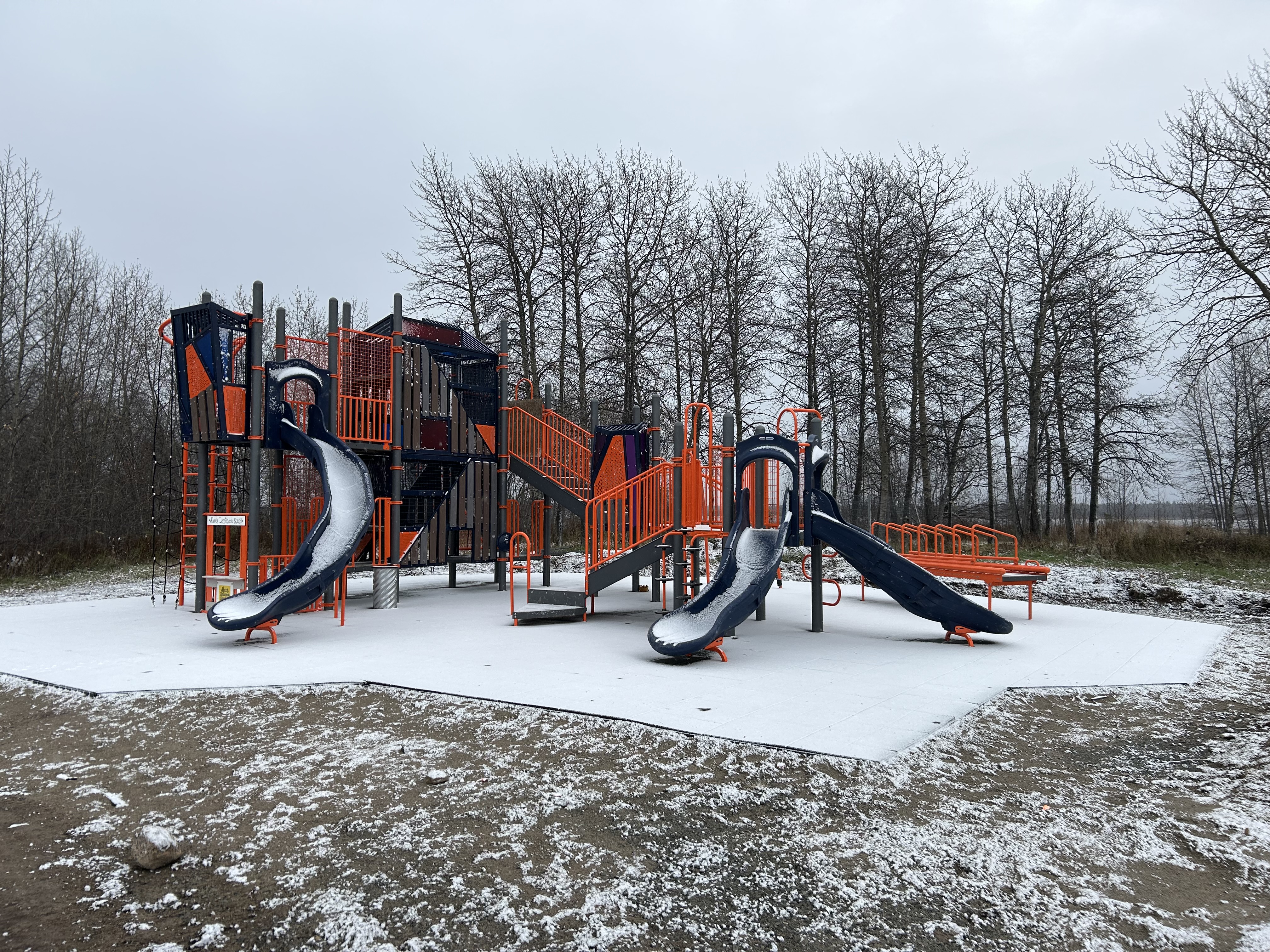 A snow-covered playground on an overcast day. 