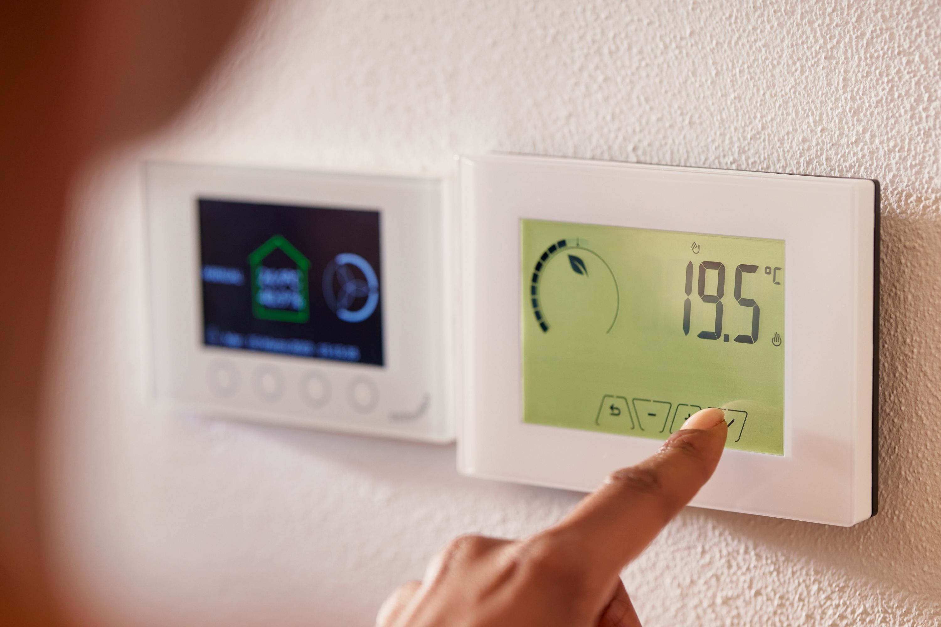 A person adjusting the temperature on a thermostat.