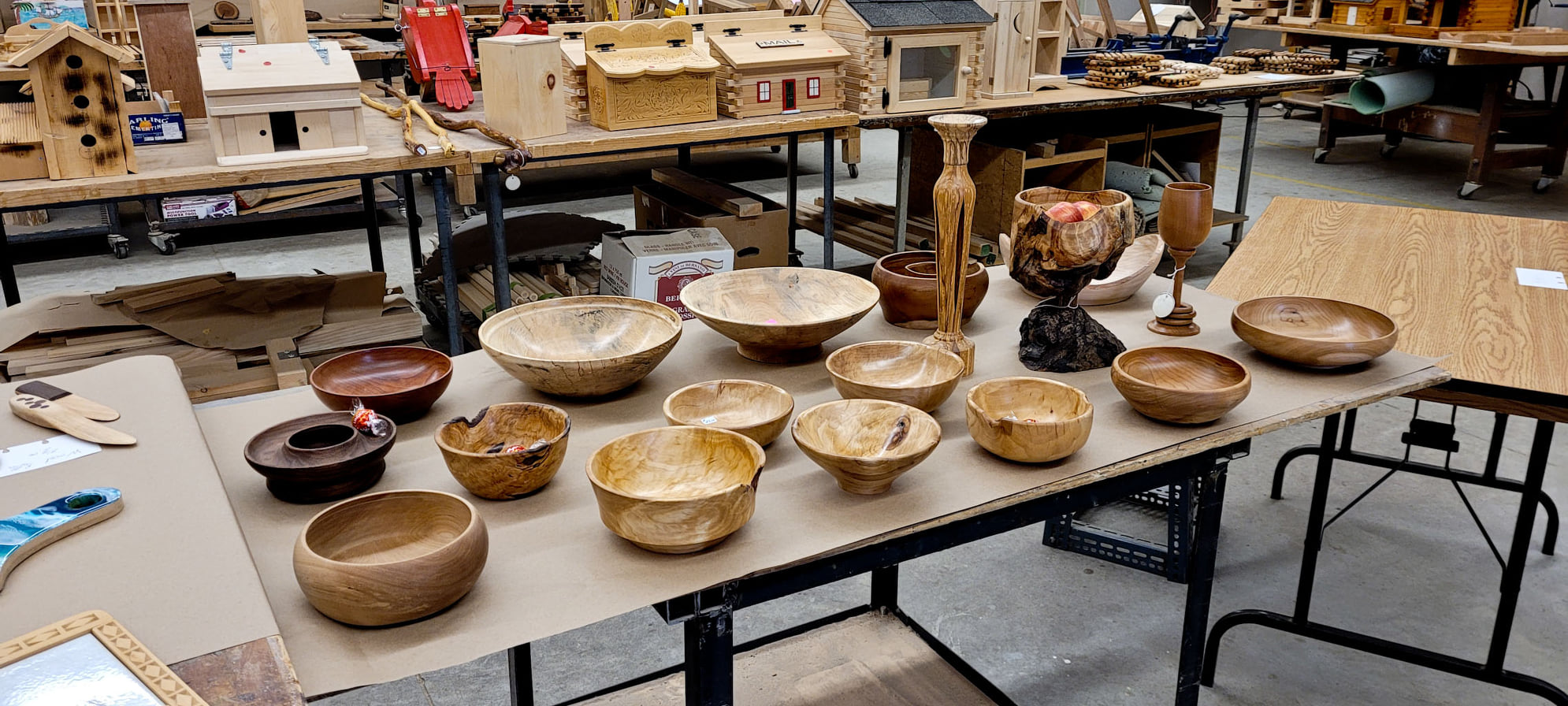 Woodworking, including bowls and other wooden crafts, are displayed on a table.