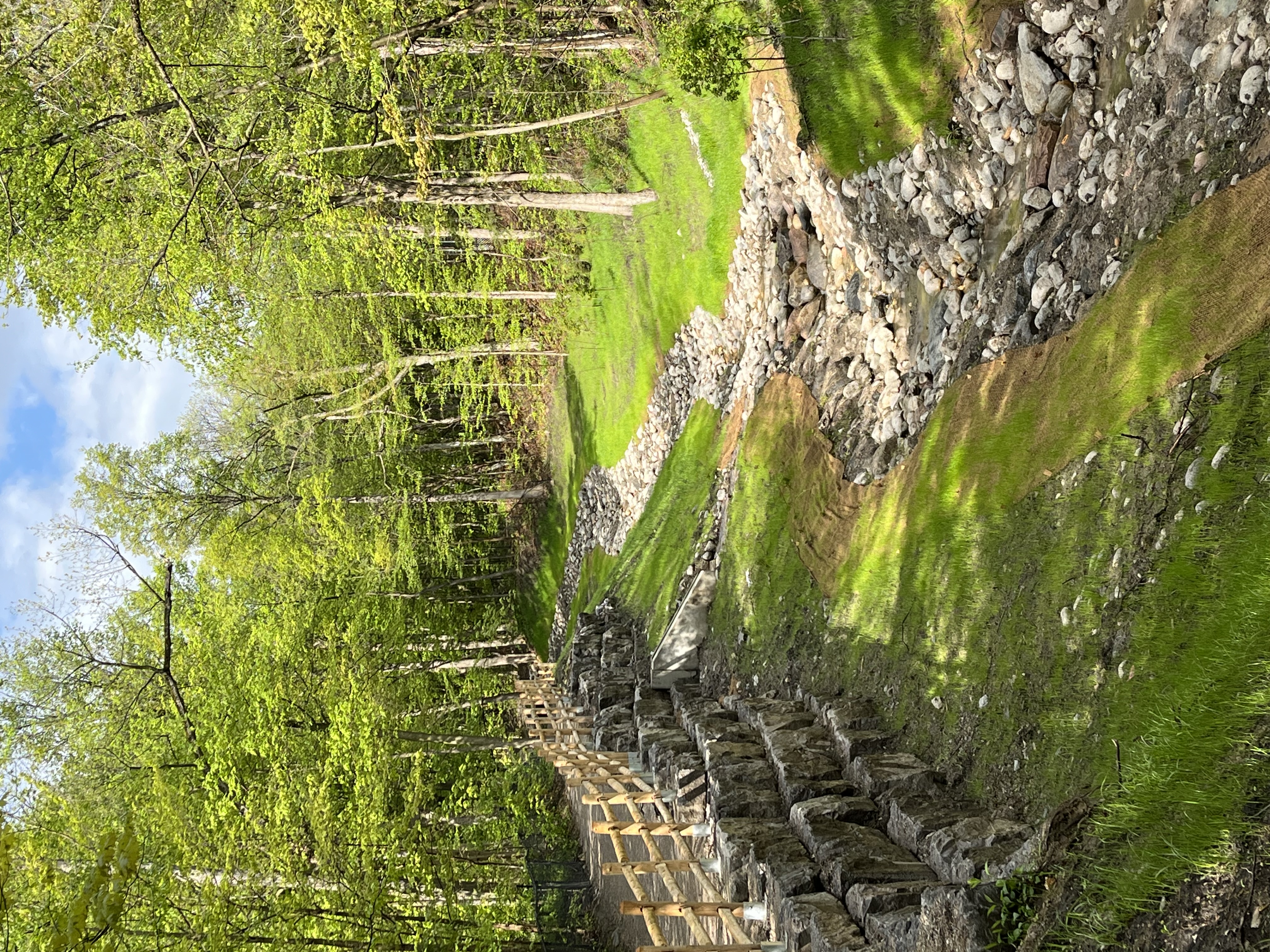 A stream in the summer with a rock retaining wall