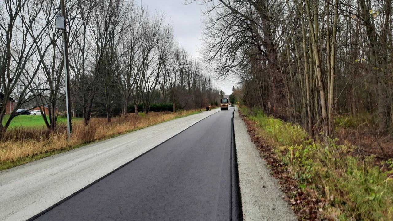 The repaved road, surrounded by trees on either side