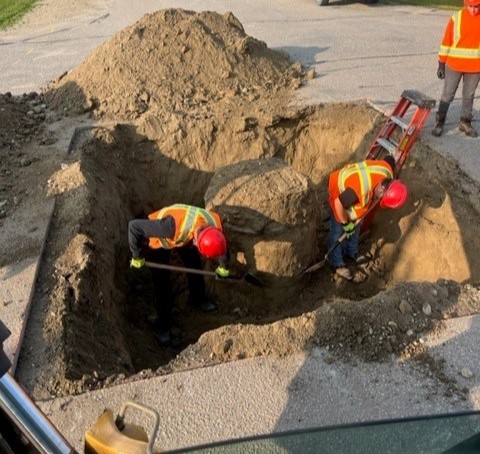 Crews digging up the ground around the manholes