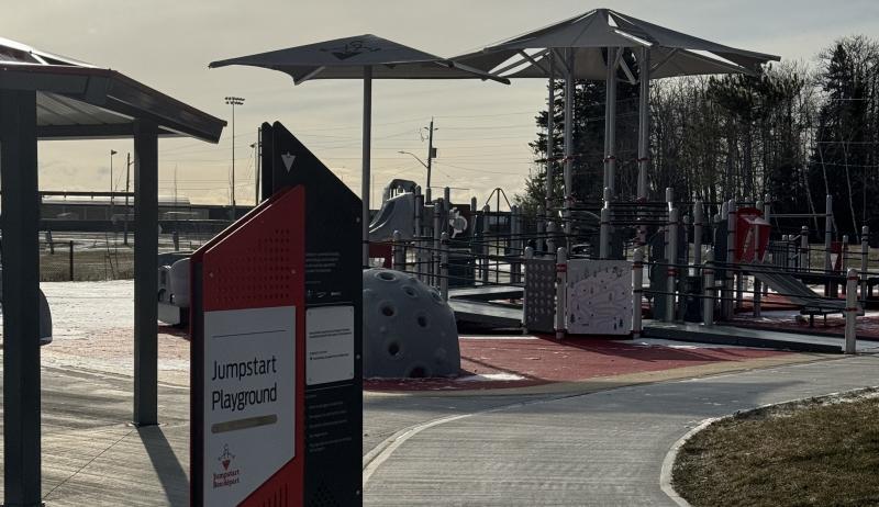 Photo of the park, featuring signage identifying the park and the play structure.