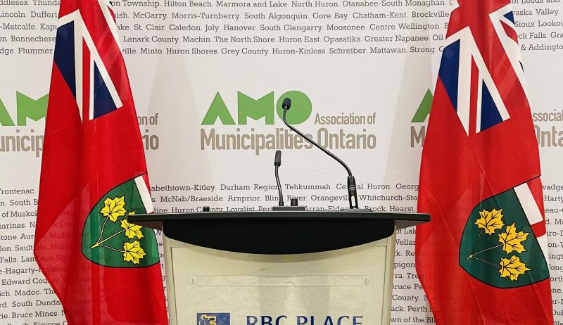 An image of a podium with a microphone and banner that reads "Association of Municipalities of Ontario".