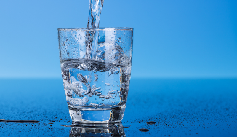 A glass of water against a blue background. 