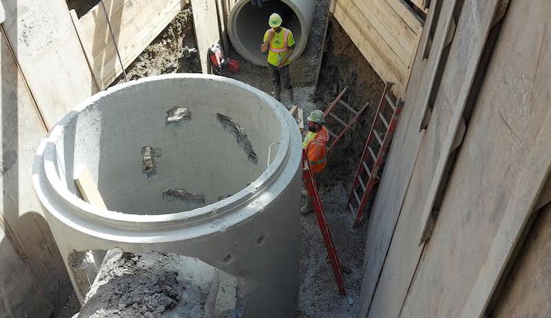 Construction workers install wastewater infrastructure underground on a street in Markham.