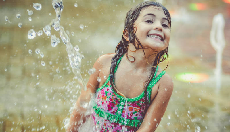 A small girl plays at a splash pad. 