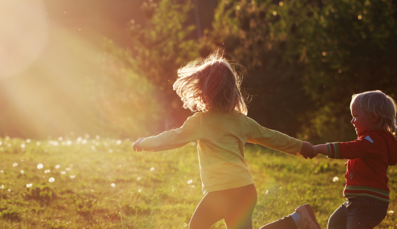 Two children running in a park. 