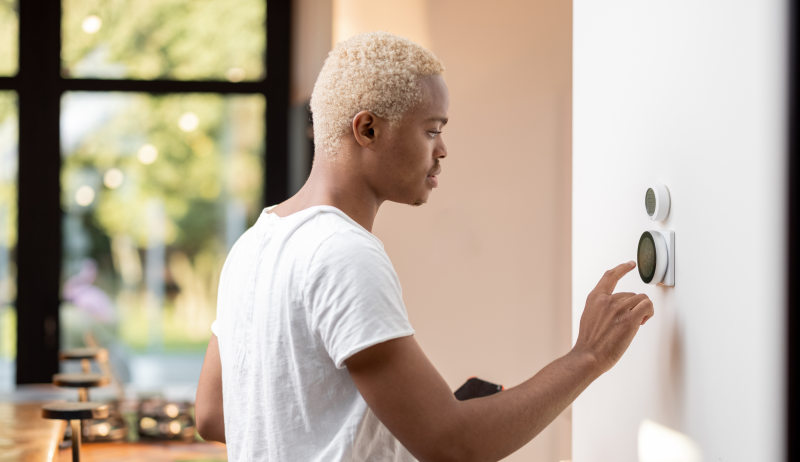 A person adjusting the temperature on a thermostat. 