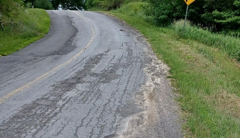 A rural roadway in poor condition. 