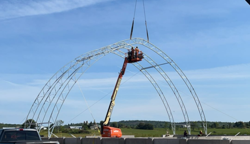 A crane putting a piece of a new sand dome on its foundation. 