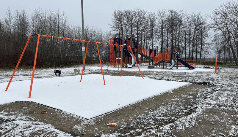 A snow-covered playground on an overcast day. 